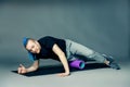 Portrait of a young man with an unusual hairstyle of mohawk from blue braids in sportswear doing leg exercise, by dint of roller Royalty Free Stock Photo