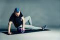 Portrait of a young man with an unusual hairstyle of mohawk from blue braids in sportswear. Doing leg exercise by dint of roller f Royalty Free Stock Photo