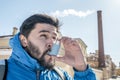 Portrait of young man using asthma inhaler outdoor Royalty Free Stock Photo