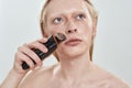 Portrait of young man using trimmer on mustache area Royalty Free Stock Photo