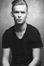 Portrait of a young man with very handsome face in black casual t-shirt and stylish haircut posing over silver metal  background. Royalty Free Stock Photo