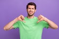 Portrait of young man wear trendy green t-shirt direct fingers himself dissatisfied dislike thumbs down isolated on Royalty Free Stock Photo