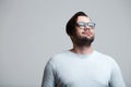 Portrait of young man wearing blue glasses, looking up over white background Royalty Free Stock Photo