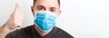 Portrait of young man wearing a medical mask at white background. Person is happy because he is finally healthy. Coronavirus