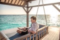 Portrait of young man wearing shirt sitting on sofa near water villas at the tropical beach at island luxury resort Royalty Free Stock Photo