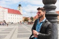 portrait of young man wearing sunglasses leaning against lighting pole