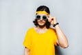 Portrait of young man wearing sunglasses and yellow shirt on grey background. Royalty Free Stock Photo