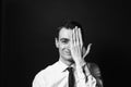 Portrait of a young man in a white shirt and black tie, hand covering half face Royalty Free Stock Photo