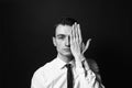 Portrait of a young man in a white shirt and black tie, hand covering half face Royalty Free Stock Photo