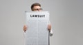 Young man keeps in front of him a poster with the inscription lawsuit isolated on a light background Royalty Free Stock Photo