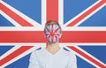 Portrait of young man in white t-shirt with face painting against British flag Royalty Free Stock Photo