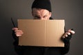 Portrait a young man who holds a felttip pen in his mouth to write text on cardboard. begging concept Royalty Free Stock Photo