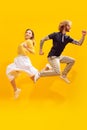 Portrait of young man and woman in casual clothes posing isolated over yellow studio background. Jumping in excitement Royalty Free Stock Photo