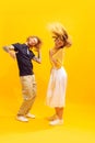 Portrait of young man and woman dancing, posing isolated over yellow studio background. Party time. Looking happy. Royalty Free Stock Photo