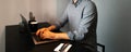 Portrait of young man working home at laptop, typing on keyboard of computer, wearing eyeglasses and shirt, sitting at desk, Royalty Free Stock Photo