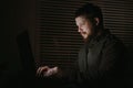 Portrait of young man working with laptop in evening at office.