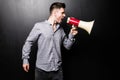 Portrait of young handsome man yelling into the megaphone over black background Royalty Free Stock Photo