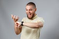 Portrait of a young man in a yellow T-shirt looks at his watch on a gray background. isolated, copyspace Royalty Free Stock Photo