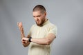 Portrait of a young man in a yellow T-shirt looks at his watch on a gray background. isolated, copyspace Royalty Free Stock Photo