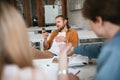 Young man with blond hair and beard sitting throw his legs on table and using cellphone in classroom. Boy with mobile Royalty Free Stock Photo