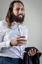 Portrait of a young middle eastern businessman with beard and long hair holding a glass of white wine and his jacket on his arm Royalty Free Stock Photo