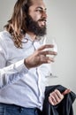 Portrait of a young middle eastern businessman with beard and long hair holding a glass of white wine and his jacket on his arm Royalty Free Stock Photo