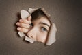 Portrait of a young Middle eastern woman peeking from ripped white paper hole Royalty Free Stock Photo
