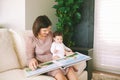 Portrait of young mother and adorable baby watching family album together