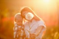 Portrait of a young mother with a child in her arms in one hand and in the other a large dandelion with white petals Royalty Free Stock Photo