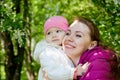 Portrait of young mother and her small daughter in the park full of apple blossom trees in a spring day. Woman and girl in nature