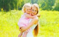 Portrait of young mother holding her little girl baby walking outdoors in summer park Royalty Free Stock Photo