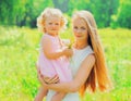 Portrait of young mother holding her little girl baby walking outdoors in summer park Royalty Free Stock Photo