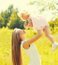 Portrait of young mother holding her little girl baby walking outdoors in summer park Royalty Free Stock Photo