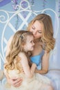 Portrait of Young mother holds her little daughter on a chair