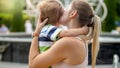 Closeup portrait of young mother hugging and caressing her crying little child boy in park Royalty Free Stock Photo