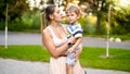 Portrait of young mother hugging her 3 years old little son and talking to him while walking in park Royalty Free Stock Photo