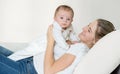 Portrait of young mother lying on bed and holding her 3 months o Royalty Free Stock Photo