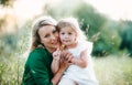 A portrait of young mother in nature with small daughter in summer.