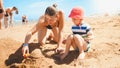 Portrait of young mother teaching her 3 years old toddler son building castles from sand on the sea beach. Family Royalty Free Stock Photo