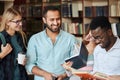 Portrait of young multicultural friends reading books together in the library Royalty Free Stock Photo