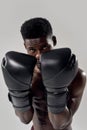 Portrait of young muscular african american male boxer looking at camera, wearing boxing gloves, standing in defence Royalty Free Stock Photo