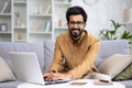 Portrait of young Muslim businessman, freelancer working from home on laptop. Typing on the keyboard and smiling at the Royalty Free Stock Photo