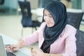 Portrait of a young Muslim businesswoman in an office, Young arabic woman in headscarf using laptop and credit card, shopping