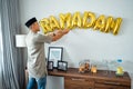muslim male decorating the wall with ramadan balloon text