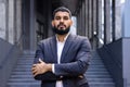 Portrait of a young Muslim male lawyer standing in a business suit outside a courthouse and looking confidently into the Royalty Free Stock Photo