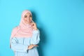 Portrait of young Muslim woman in hijab against color background.