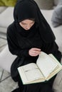 Portrait of young muslim woman reading Quran in modern home