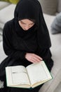 Portrait of young muslim woman reading Quran in modern home