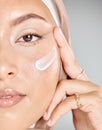 Portrait of a young Muslim woman wearing a hijab or headscarf applying a cream moisturizer on her flawless skin while Royalty Free Stock Photo