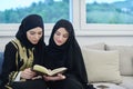 Portrait of young muslim women reading Quran in modern home.